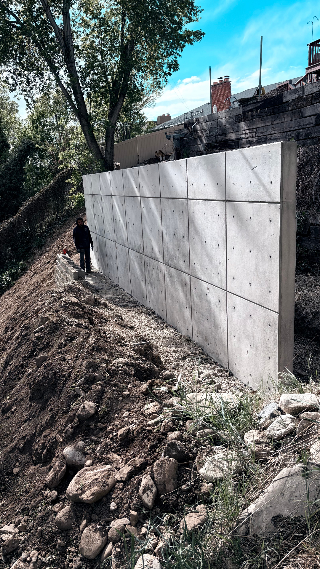 Tall poured concrete retaining wall on hillside