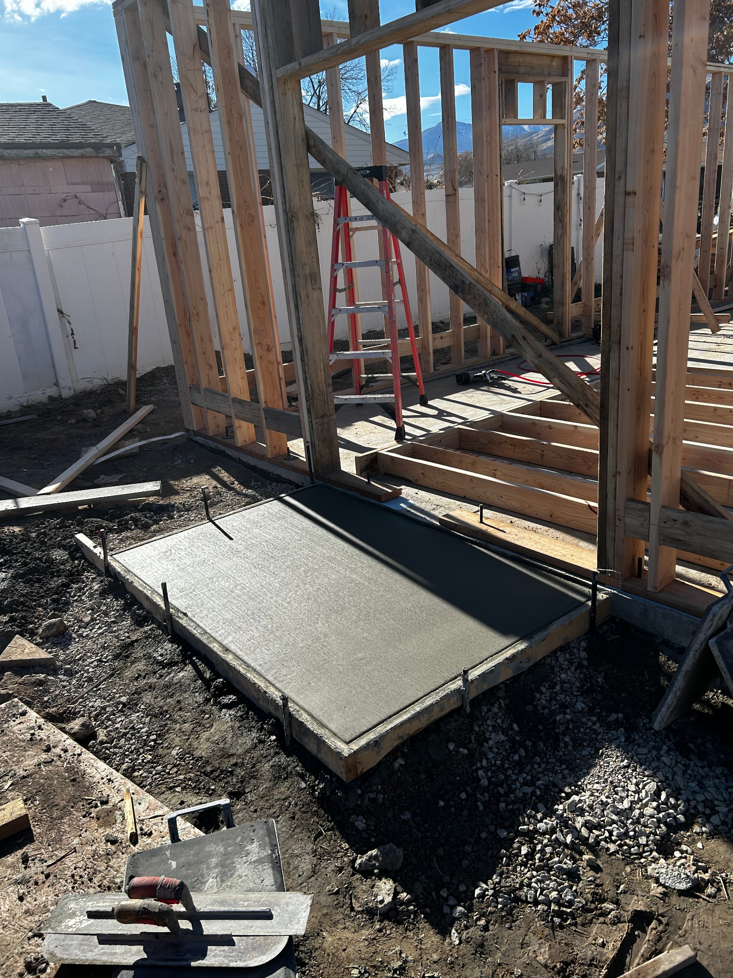 Fresh broom finished concrete entry slab beside framed home addition